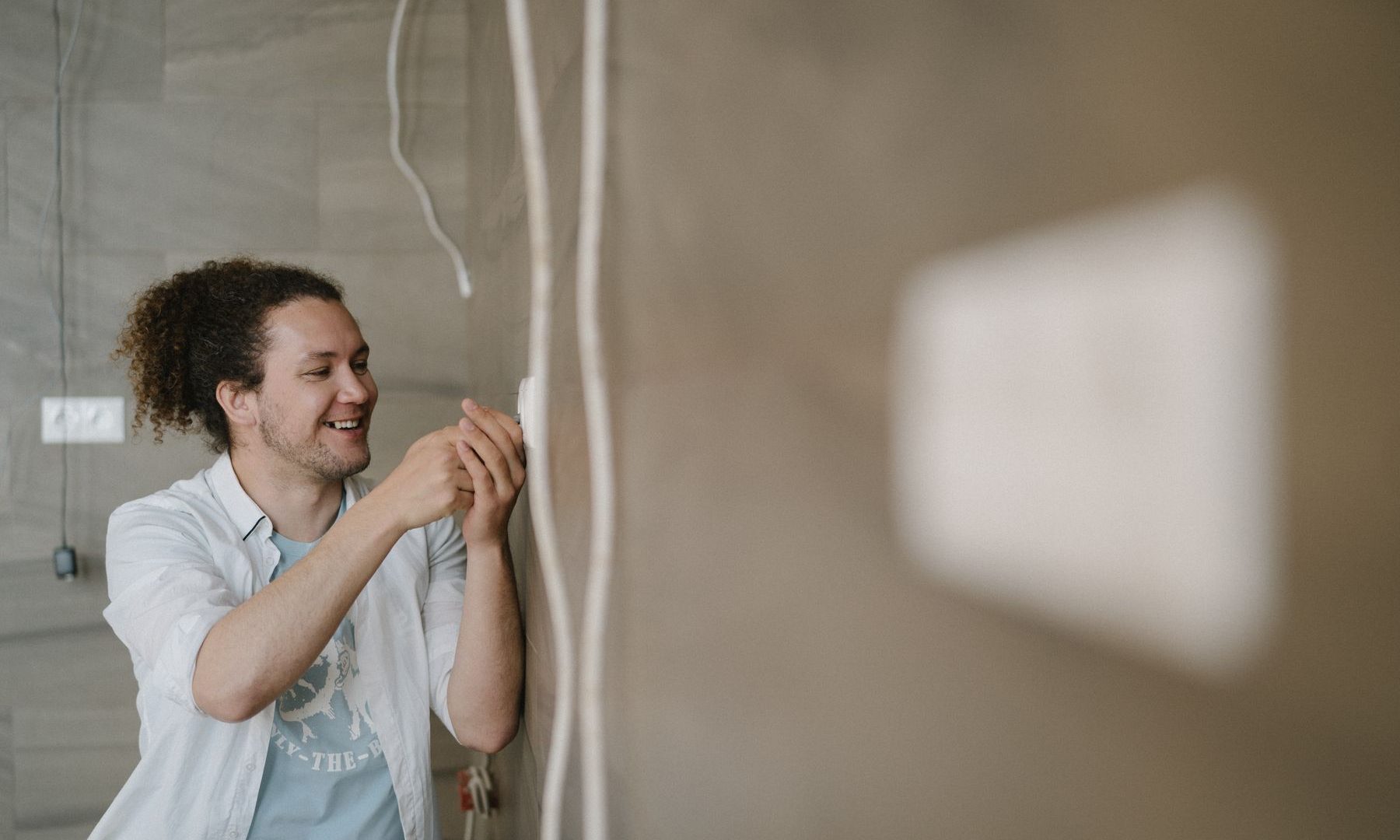 Installateur verlegt eine Leitung an einer Wand im Rohbau