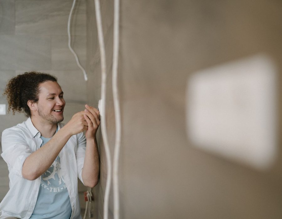 Installateur verlegt eine Leitung an einer Wand im Rohbau