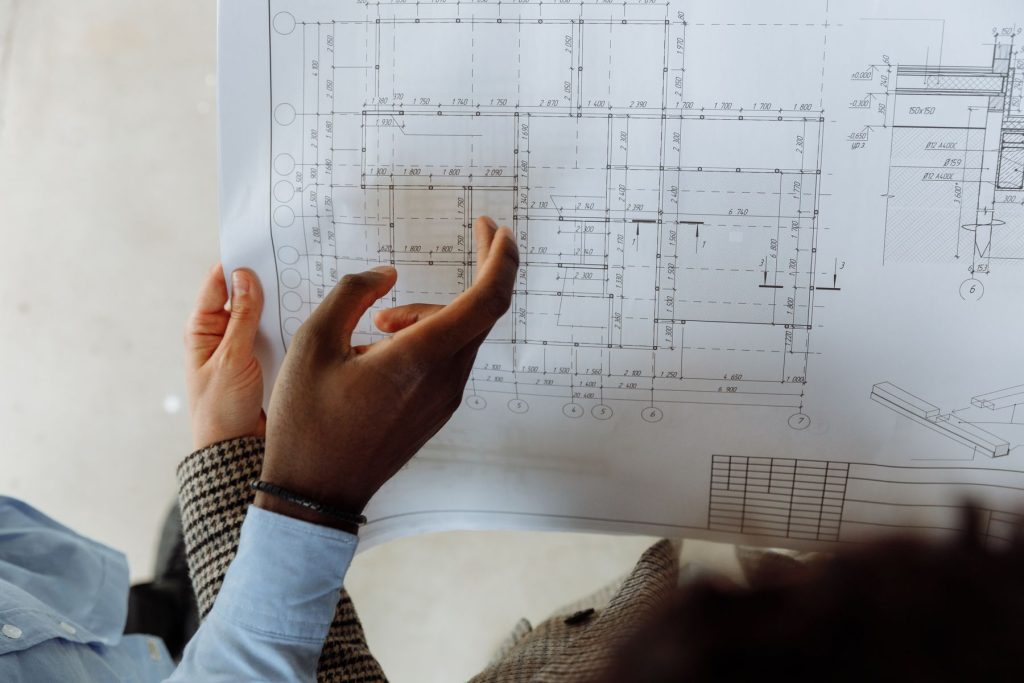 Hände halten einen Grundrissplan bei der Projektbesprechung