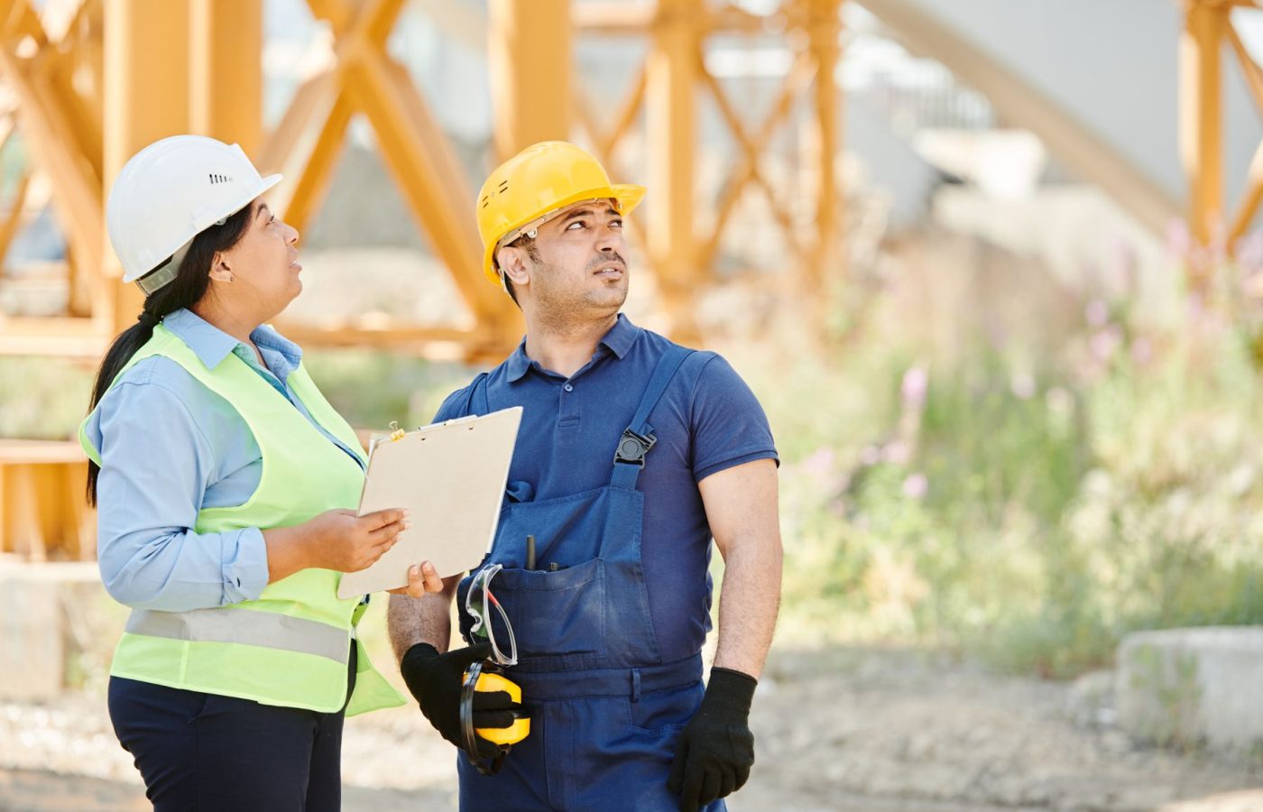 Bauleiterin und Handwerker besprechen die Arbeiten mit Klemmbrett auf der Baustelle