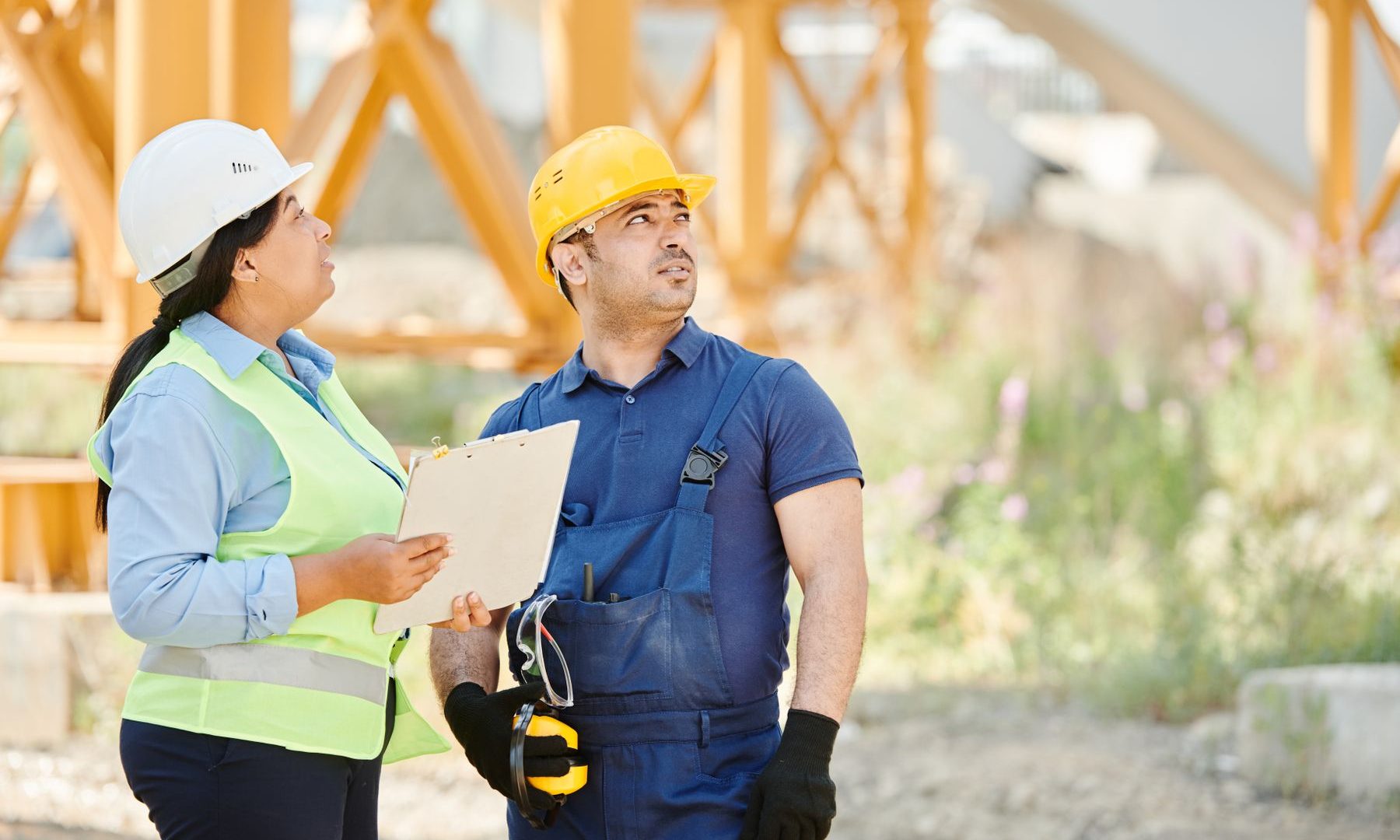 Bauleiterin und Handwerker besprechen die Arbeiten mit Klemmbrett auf der Baustelle